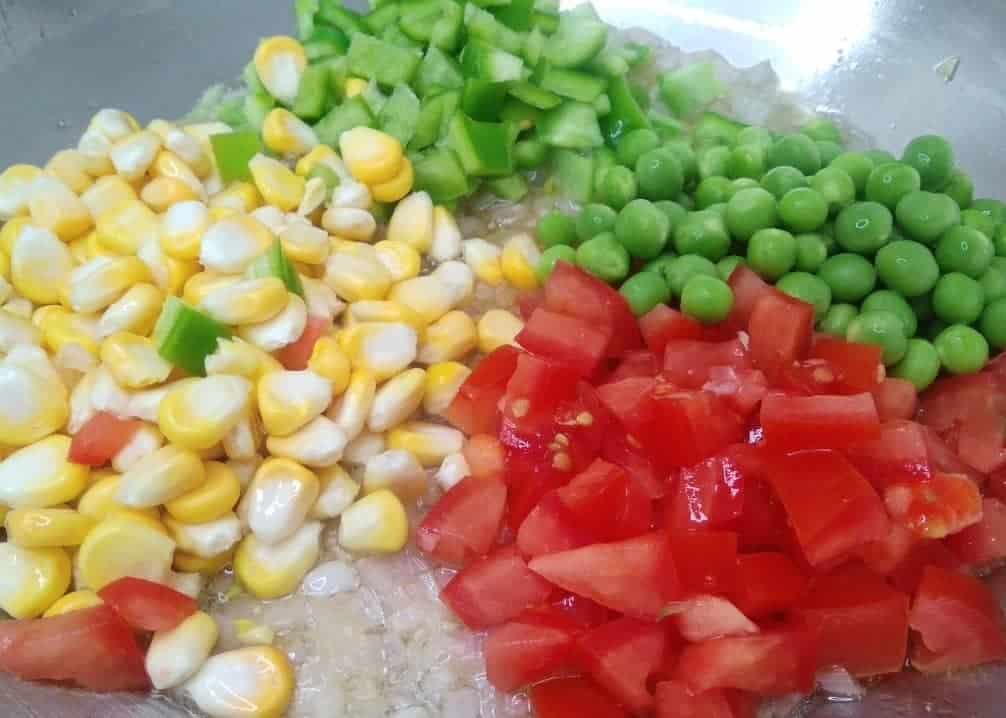 Add ½ cup tomato, ½ cup corn, ¼ cup green peas, and ¼ cup capsicum